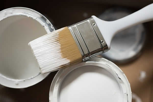 paint brush resting on cans of paint