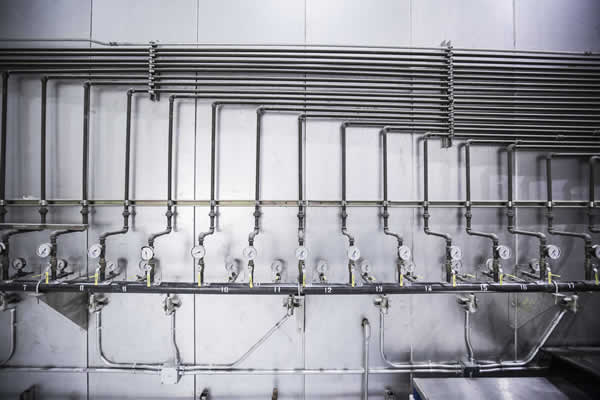 numerous pipes, pressure gauges and valves mounted on wall