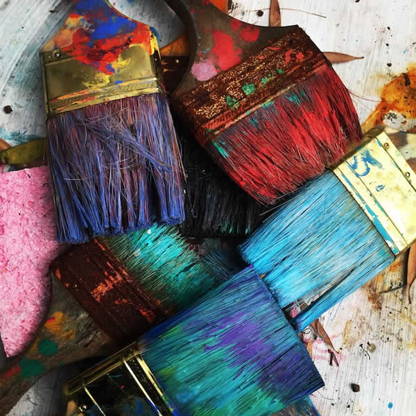 paint brushes covered in colorful paint